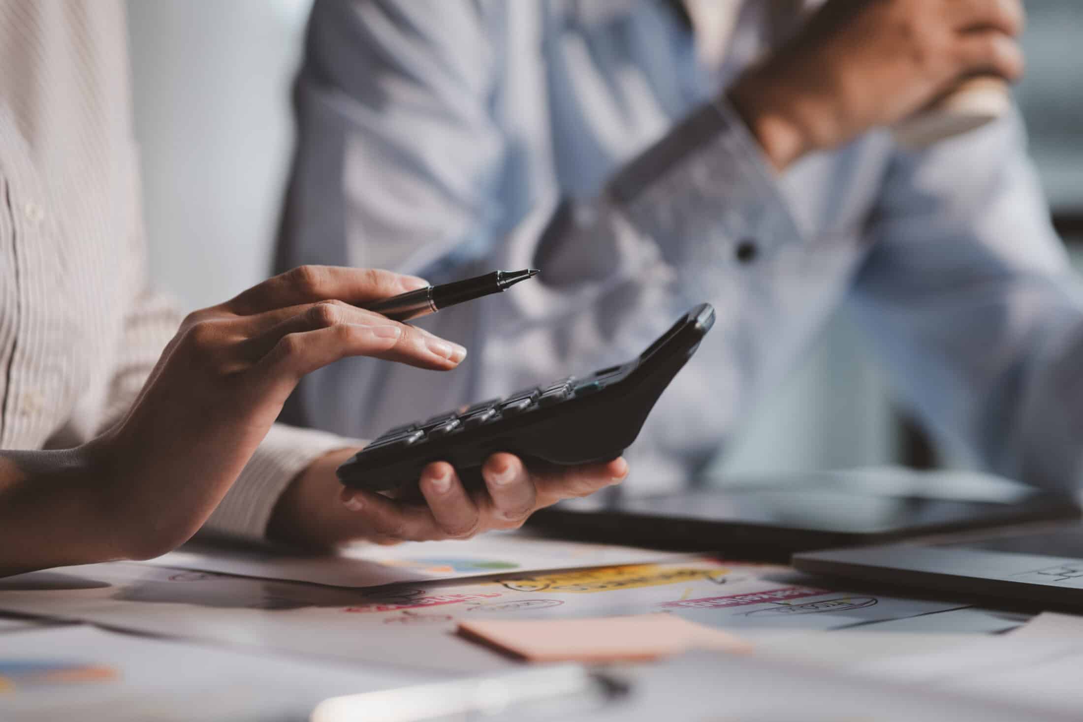 une femme utilise une calculatrice pour calculer si elle doit louer ou acheter sa caisse enregistreuse